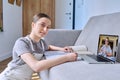 Teenage girl studying at home, using laptop, looking at camera Royalty Free Stock Photo