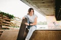 Teenage girl in stylish clothes posing on half pipe ramp an outdoor skate park. Beautiful kid female model skateboarder with skate Royalty Free Stock Photo