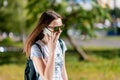 A teenage girl is talking on the phone. In the summer in the park in nature. Brunette in sunglasses. A schoolgirl after