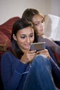 Teenage girl texting while sister watches Royalty Free Stock Photo