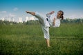 Teenage girl training karate kata outdoors, performs the uro mawashi geri hook kick Royalty Free Stock Photo