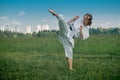 Teenage girl training karate kata outdoors, performs the uro mawashi geri hook kick Royalty Free Stock Photo