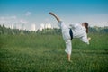 Teenage girl training karate kata outdoors, performs the uro mawashi geri hook kick Royalty Free Stock Photo