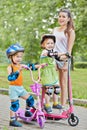 Teenage girl and two little children on scooters Royalty Free Stock Photo