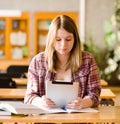 Teenage girl using electronic tablet at library