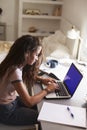 Teenage girl using laptop at a desk in her bedroom, vertical Royalty Free Stock Photo