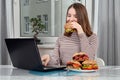 Teenage girl using a laptop and eating a vegetarian sandwich Royalty Free Stock Photo