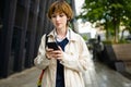 Teenage girl using a smart phone. Beautiful young girl in a city park on autumn day. Teenagers addiction to new technology Royalty Free Stock Photo