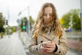 Teenage girl using a smart phone. Beautiful young girl in a city park on autumn day. Teenagers addiction to new technology Royalty Free Stock Photo