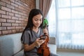 Teenage girl violinist holding a cell phone while sitting on an indoor sofa