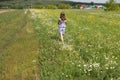 Teenage girl walking in a beautiful clearing near a house in the village, rear view,copy space Royalty Free Stock Photo