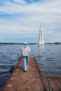 A teenage girl walks with her back to the camera along a boat pier .