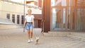 Teenage girl walks with puppy on leash on yard pavement