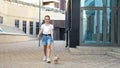 Teenage girl walks with puppy on leash on yard pavement