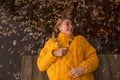 A teenage girl lies on a wooden bridge, holding her head above the dark water in which fallen leaves float Royalty Free Stock Photo