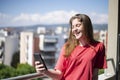 Teenage Girl Watching Her Mobile Phone at the Balcony and Laughing Royalty Free Stock Photo
