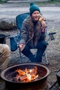 Teenage girl wearing beanie hat eating large marshmallow on a stick roasted over the campfire firepit. Camping family fun Royalty Free Stock Photo