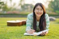 Teenage girl wearing glasses lying down with guitar and books On the field at sunset Royalty Free Stock Photo