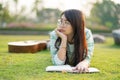 Teenage girl wearing glasses lying down with guitar and books On the field at sunset. Royalty Free Stock Photo