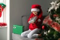 A teenage girl wearing a Santa Claus hat received a gift and looks at it with a smile. Christmas and New Year