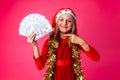 a teenage girl, wearing a Santa hat and with tinsel on her neck, with dollars in her hands, and points at them with her finger is Royalty Free Stock Photo