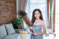 Teenage girl wearing a smiling apron while holding a feather duster looking at the camera