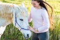 Teenage girl with a white Boerperd horse standing by his head petting his nose Royalty Free Stock Photo