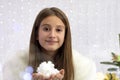 teenage girl in winter clothes a white fur coat,holds artificial snow,demonstrates to the camera,smiles,against the backdrop of Royalty Free Stock Photo