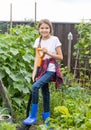 Smiling teenage girl working in garden and diggin earth