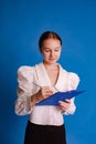 teenage girl write notes on binder folder for paper documents  on light blue studio background Royalty Free Stock Photo