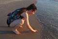 A teenage girl writes on the sand in the beach Royalty Free Stock Photo
