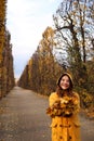 Teenage girl in a yellow hooded coat holds the leaves in her hands Augarten park Vienna autumn