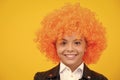 Teenage girl with yellow wig. Funny child wearing orange curly wig hair. Happy girl face, positive and smiling emotions. Royalty Free Stock Photo