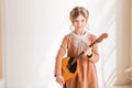 A teenage girl a young musician plays a stringed musical instrument dombra in the classroom at a music lesson. Background of