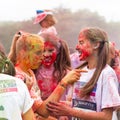 Teenage girls celebrate after completing a Colour Paint Run. Two girls are laughing and one is scowling and pointing