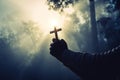 Teenage girls pray with a cross in a sunny nature. The girl sat in the green forest with sunlight.