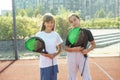 Teenage girls with racquets and balls standing in padel court, looking at camera and smiling. Royalty Free Stock Photo