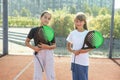 Teenage girls with racquets and balls standing in padel court, looking at camera and smiling. Royalty Free Stock Photo