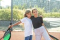 Teenage girls with racquets and balls standing in padel court, looking at camera and smiling. Royalty Free Stock Photo