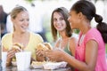 Teenage Girls Sitting Outdoors Eating Fast Food