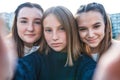 3 teenage girls. They take pictures themselves on phone, happy smiles play have fun. Online application Internet, social