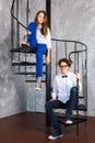 Teenage girls wearing glasses and sneakers sitting on spiral staircase in loft apartment. Teenagers in white shirts Royalty Free Stock Photo