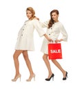 Teenage girls in white coats with shopping bags Royalty Free Stock Photo