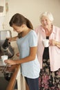 Teenage Granddaughter Sharing Cup Of Tea With Grandmother In Kitchen Royalty Free Stock Photo