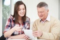 Teenage Granddaughter Showing Grandfather How To Use Digital Tab