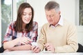 Teenage Granddaughter Showing Grandfather How To Use Mobile Phone