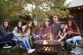 Teenage group sitting around a fire pit smiling to camera Royalty Free Stock Photo