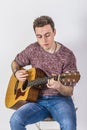 Teenage guitar player sits on a chair and plays western guitar Royalty Free Stock Photo