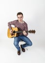 Teenage guitar player sits on a chair and plays western guitar Royalty Free Stock Photo