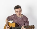 Teenage guitar player sits on a chair and plays western guitar Royalty Free Stock Photo